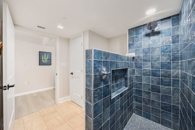 bathroom with tiled shower and hardwood / wood-style flooring