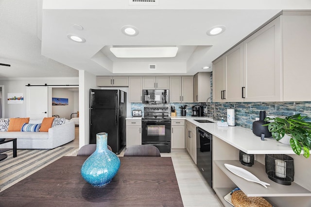 kitchen with tasteful backsplash, gray cabinetry, light hardwood / wood-style floors, sink, and black appliances