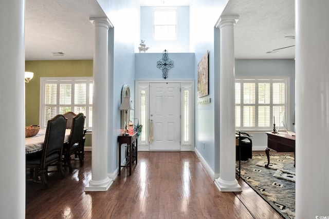 foyer entrance featuring ornate columns and dark hardwood / wood-style floors