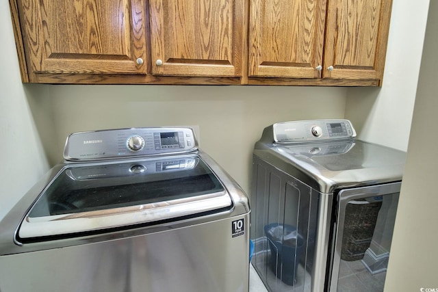 laundry room with washer and clothes dryer, tile patterned floors, and cabinets