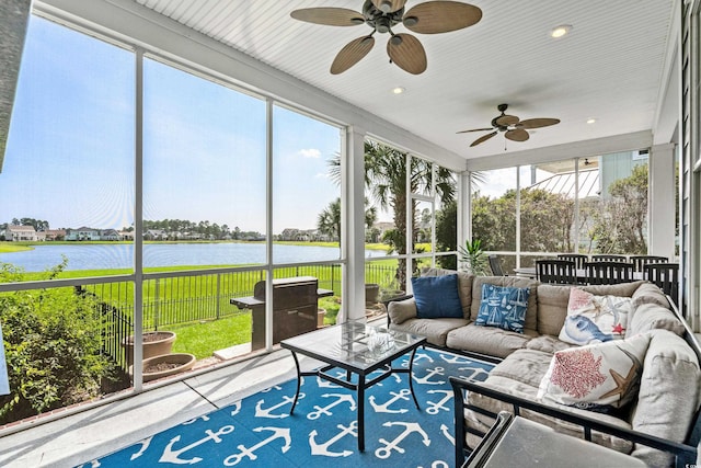 sunroom / solarium with ceiling fan and a water view