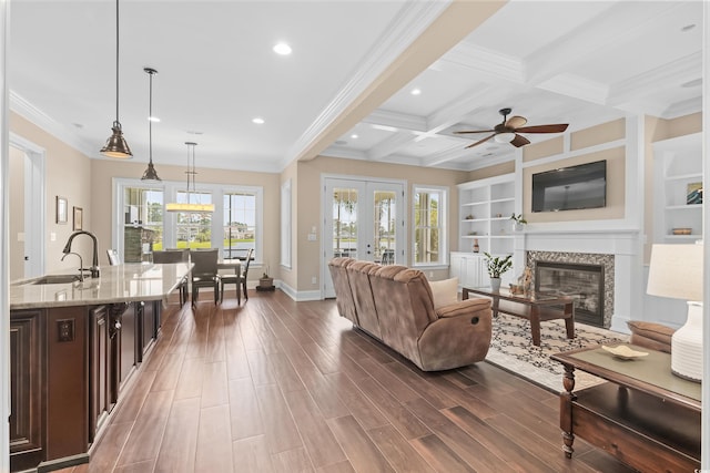 living room featuring sink, coffered ceiling, plenty of natural light, and beam ceiling