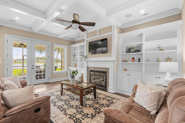 living room with french doors, light wood-type flooring, ceiling fan, beam ceiling, and ornamental molding