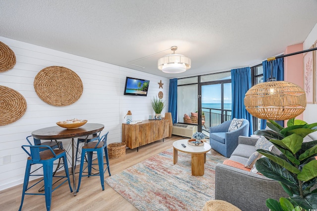 living room featuring wood walls, a textured ceiling, and hardwood / wood-style flooring