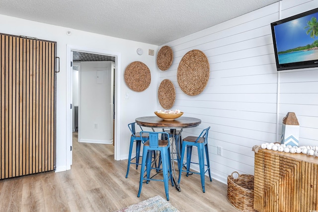 dining area featuring a textured ceiling and light hardwood / wood-style flooring