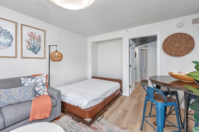 bedroom with light wood-type flooring and a textured ceiling