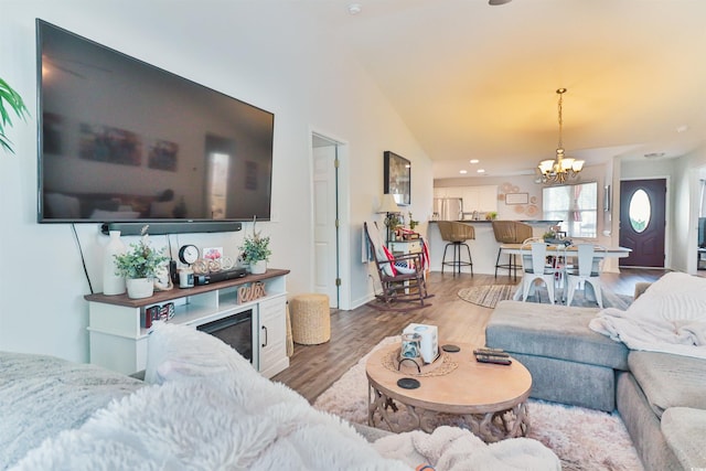 living room with a notable chandelier, lofted ceiling, and hardwood / wood-style flooring