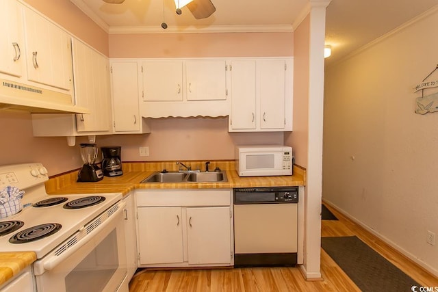 kitchen featuring crown molding, under cabinet range hood, light wood-style floors, white appliances, and a sink