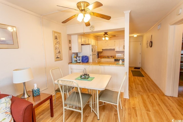 dining area with visible vents, baseboards, light wood-style floors, and ornamental molding