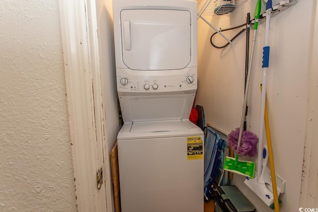 laundry room with laundry area, stacked washer / dryer, and a textured wall