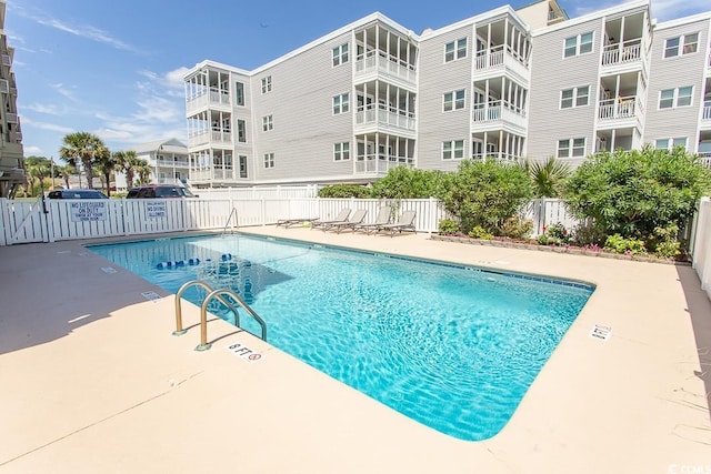 pool with a patio area and fence