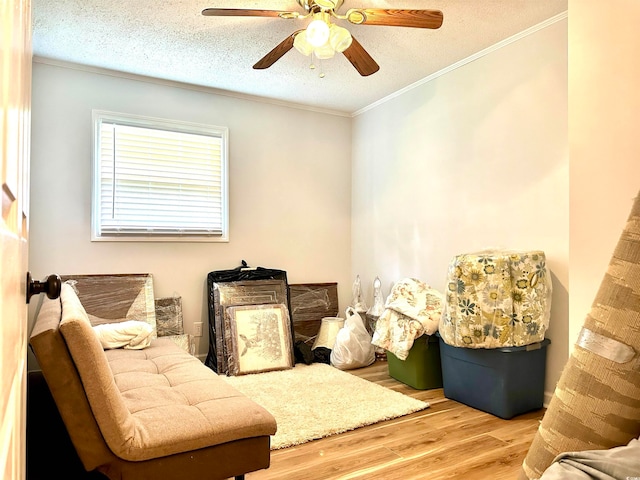 living area featuring a textured ceiling, ceiling fan, ornamental molding, and wood-type flooring