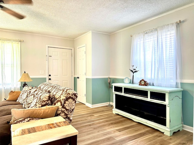 living room featuring ceiling fan, a textured ceiling, crown molding, and wood-type flooring