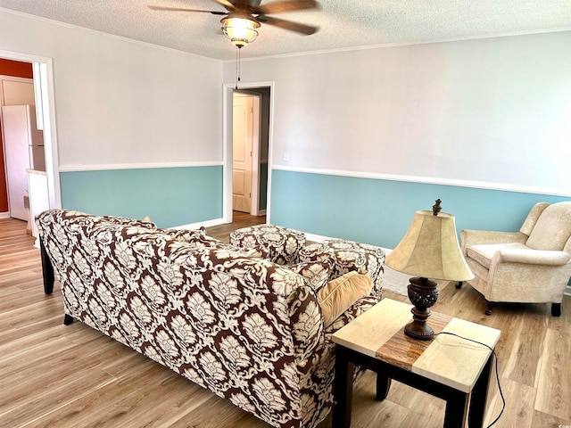 living room featuring ceiling fan, light hardwood / wood-style floors, and a textured ceiling