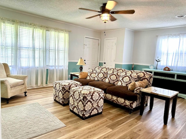 living room with light hardwood / wood-style floors, crown molding, ceiling fan, and a textured ceiling