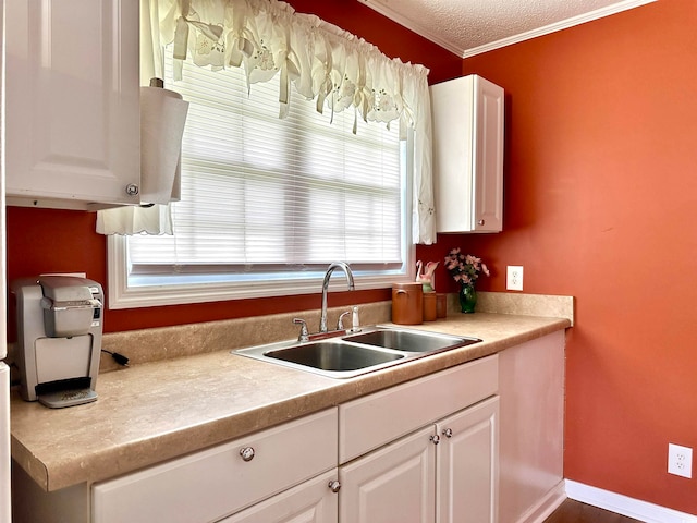 kitchen with sink, crown molding, white cabinetry, and a textured ceiling