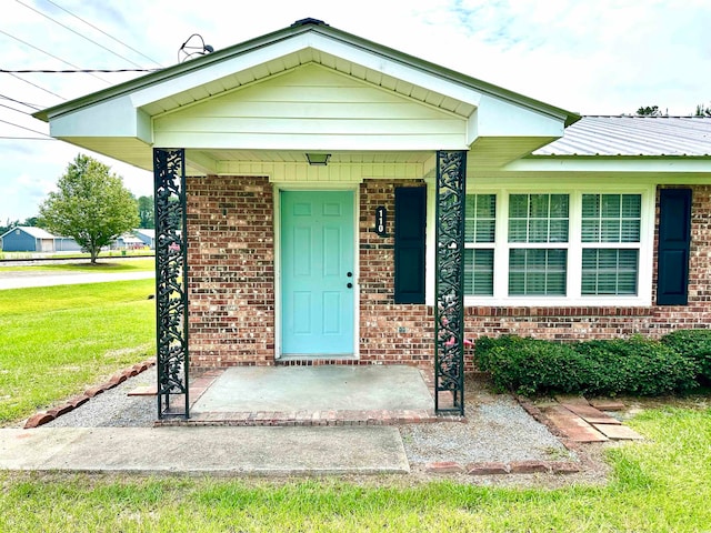 view of exterior entry featuring a lawn