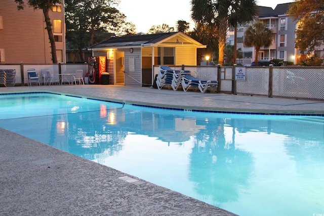 pool at dusk with a patio area