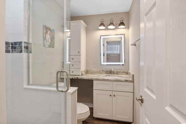 bathroom with wood-type flooring, an enclosed shower, vanity, and toilet