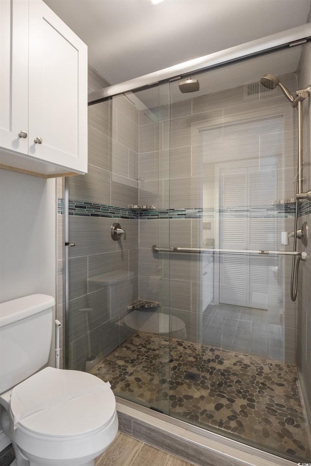 bathroom with wood-type flooring, toilet, and an enclosed shower