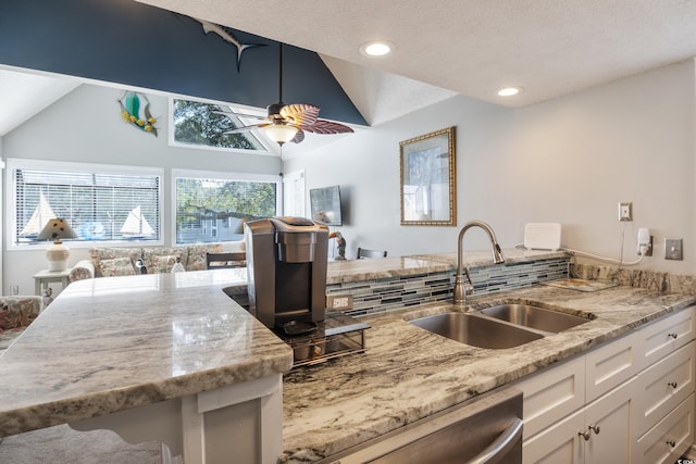 kitchen featuring ceiling fan, white cabinets, lofted ceiling, sink, and stainless steel dishwasher