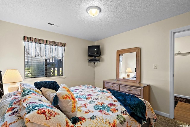 bedroom with a textured ceiling and hardwood / wood-style flooring