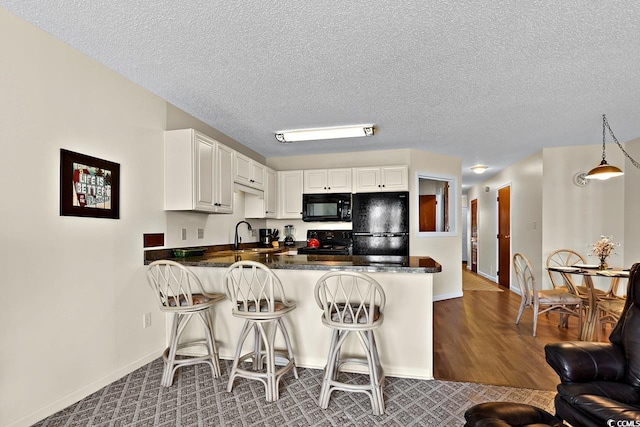 kitchen with hardwood / wood-style flooring, kitchen peninsula, hanging light fixtures, and black appliances