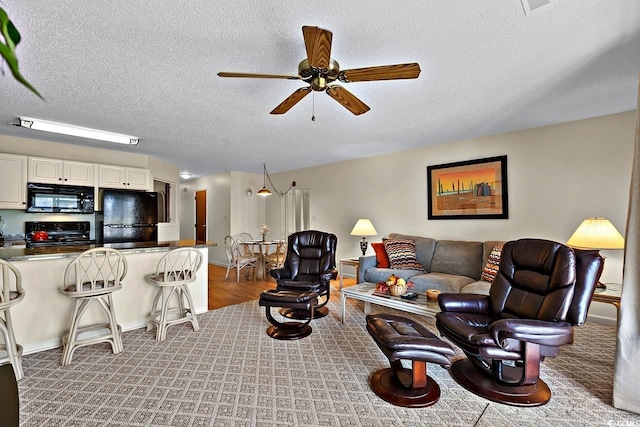 carpeted living room with ceiling fan and a textured ceiling