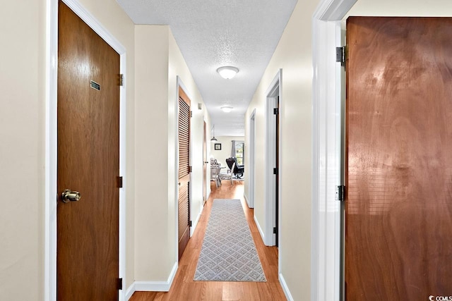 hallway featuring light hardwood / wood-style flooring and a textured ceiling