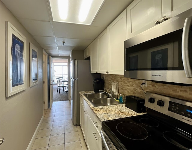 kitchen with sink, white cabinets, backsplash, appliances with stainless steel finishes, and light tile patterned floors