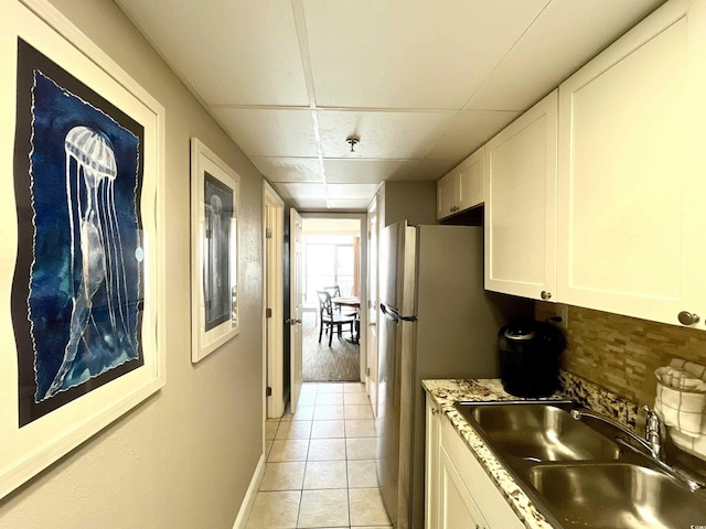 kitchen featuring white cabinets, sink, light tile patterned floors, tasteful backsplash, and a paneled ceiling