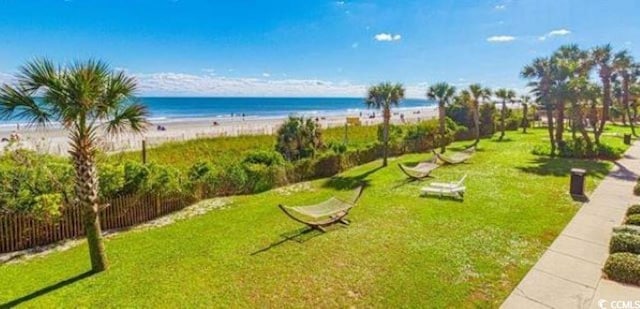 view of home's community with a lawn, a water view, and a view of the beach