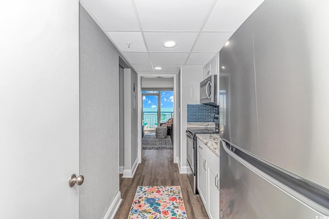 hall featuring a drop ceiling and dark wood-type flooring