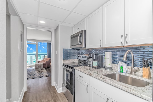 kitchen with decorative backsplash, light hardwood / wood-style flooring, white cabinetry, sink, and stainless steel appliances