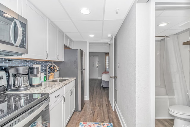 kitchen featuring light wood-type flooring, a paneled ceiling, tasteful backsplash, and range with electric stovetop