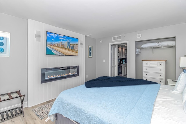 bedroom with a closet, a spacious closet, and light hardwood / wood-style flooring