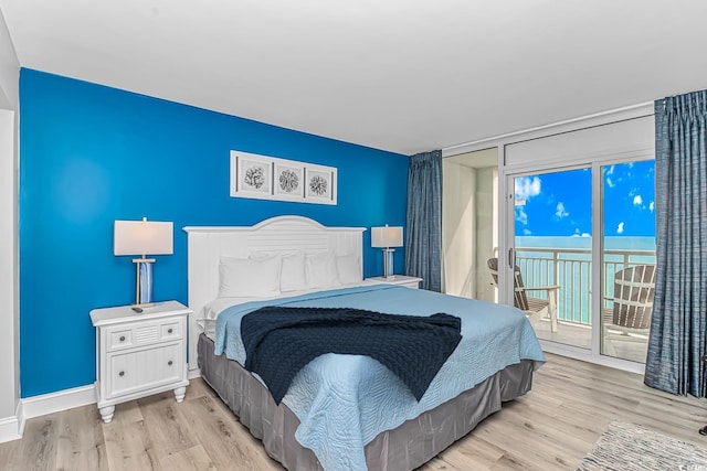 bedroom featuring a water view, access to outside, and light hardwood / wood-style floors