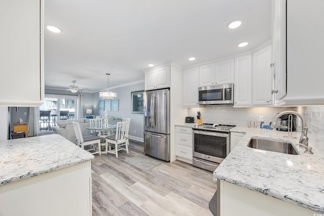 kitchen with appliances with stainless steel finishes, backsplash, a sink, and white cabinets