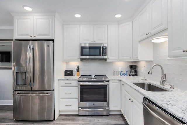 kitchen with tasteful backsplash, white cabinets, light stone counters, stainless steel appliances, and a sink