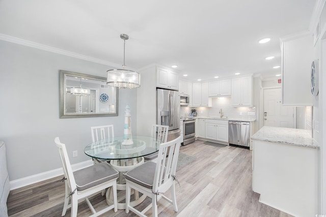 dining area featuring crown molding, light wood finished floors, recessed lighting, and baseboards