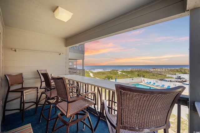 balcony at dusk featuring a water view