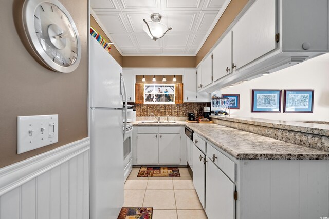 kitchen featuring white cabinetry, tasteful backsplash, sink, light tile patterned floors, and white fridge