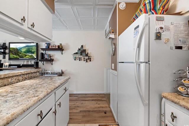 kitchen with white cabinetry, white fridge, and hardwood / wood-style flooring