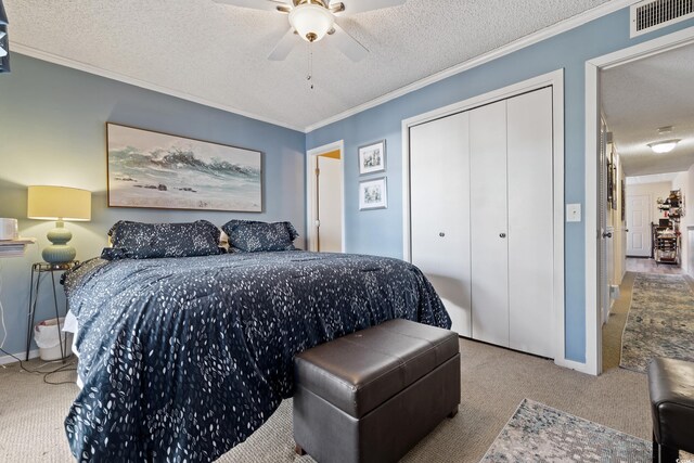 carpeted bedroom featuring a textured ceiling, a closet, ceiling fan, and ornamental molding