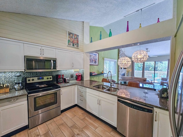 kitchen with appliances with stainless steel finishes, white cabinets, a textured ceiling, and sink