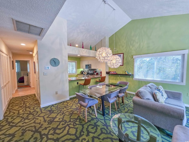 dining area featuring baseboards, visible vents, carpet flooring, high vaulted ceiling, and a wealth of natural light