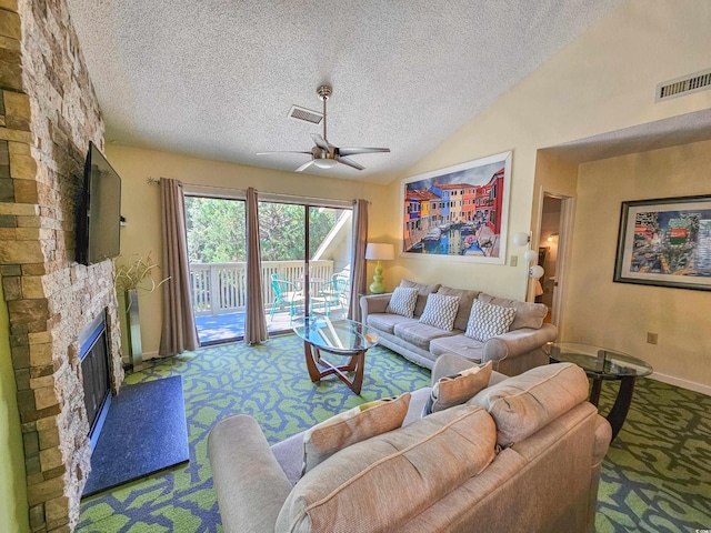 living room featuring ceiling fan, a stone fireplace, a textured ceiling, carpet floors, and lofted ceiling