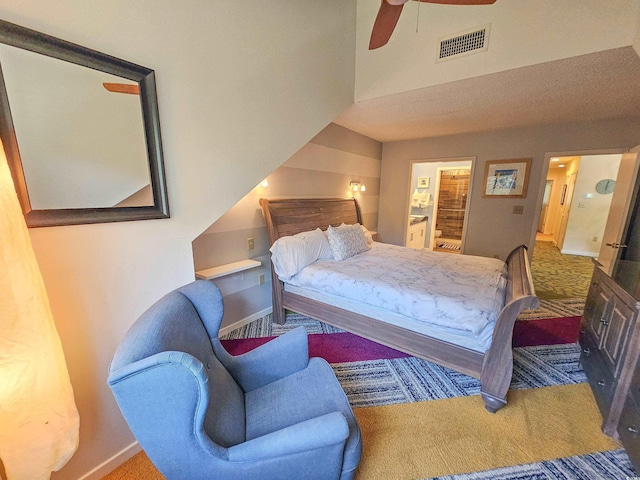 carpeted bedroom featuring ensuite bathroom, baseboards, visible vents, and a ceiling fan