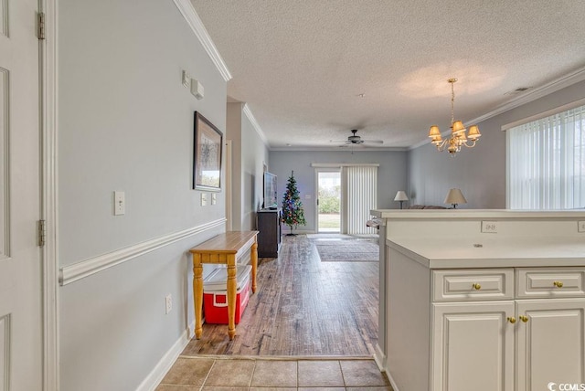 kitchen featuring ceiling fan with notable chandelier, light hardwood / wood-style floors, ornamental molding, and a textured ceiling