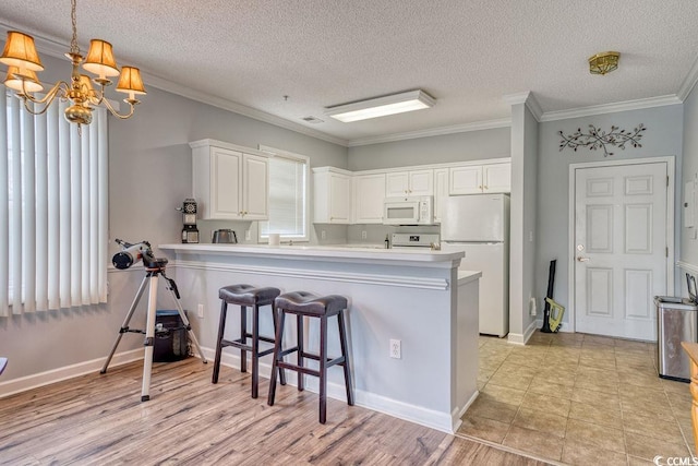 kitchen with light wood-type flooring, white appliances, kitchen peninsula, and white cabinets